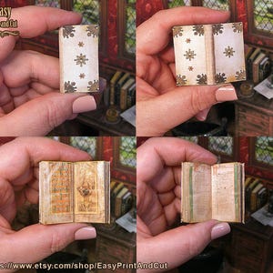 May include: A miniature book with a cream cover featuring brown floral and starburst patterns. The pages are aged, with illustrations and text. The book is held in a hand, highlighting its small size and intricate details. The text "Easy Print and Cut" is visible.
