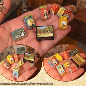 Könnte beinhalten: Eine Sammlung von Miniatur-Vintage-Boxen, darunter Tee-, Gewürz- und andere Produktverpackungen. Die Boxen sind in verschiedenen Farben gehalten und weisen detaillierte Grafiken und Texte auf. Das Bild zeigt eine Nahaufnahme der Boxen in einer Hand.
