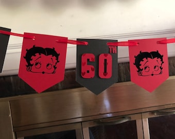 May include: A red and black banner with a cartoon character and the number 60 with the word "TH" above it. The banner is decorated with red hearts.