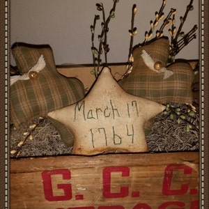 May include: A wooden box with the text "G.C.C. EVERAGE" printed in red. The box contains three fabric stars, one with the text "March 17 1764" written on it.