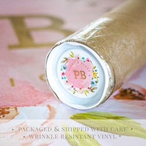 May include: Close-up of a rolled-up print with a floral design and the initials "PB" in a circle. The print is packaged in a brown tube with a white end cap.