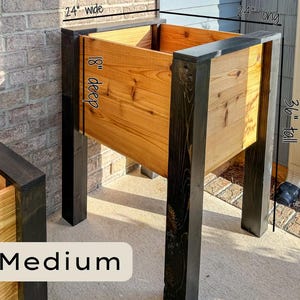 May include: A medium-sized wooden planter box with a natural wood finish and dark stained legs. The planter is 24 inches wide, 24 inches long, 18 inches deep, and 36 inches tall. The word "Medium" is displayed at the bottom.
