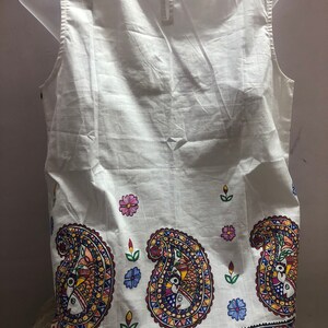 May include: White sleeveless top with a paisley print in shades of blue, red, yellow, and green. The print features stylized birds and flowers.