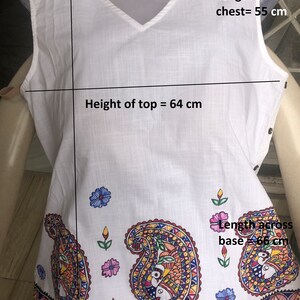 May include: White sleeveless top with a V-neck and a paisley print. The top measures 64 cm in height and 55 cm across the chest. The base of the top measures 66 cm across.