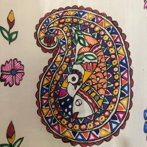 May include: A white fabric with a colorful paisley design. The paisley is filled with geometric shapes and a peacock design. The fabric is decorated with other floral designs.