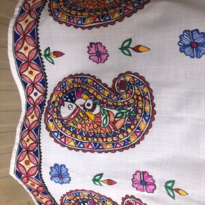May include: White fabric with a paisley pattern in red, blue, yellow, green, and orange. The paisley pattern is repeated three times on the fabric. The fabric is decorated with small flowers in pink, blue, and yellow.