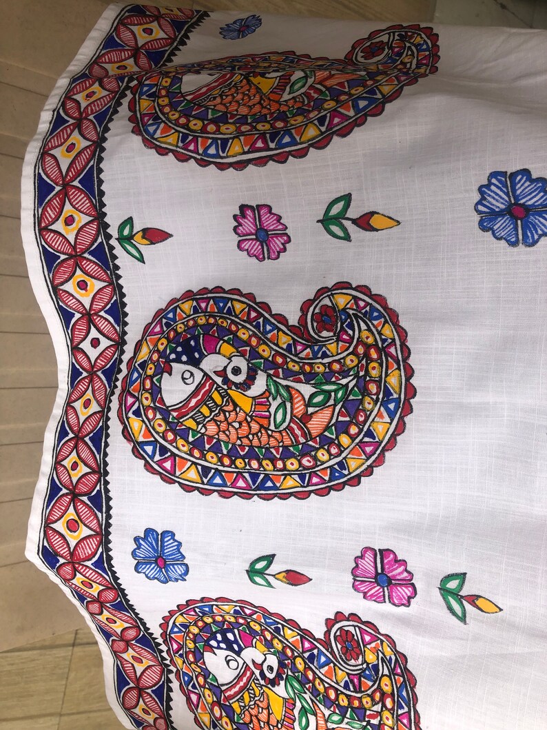 May include: White fabric with a paisley pattern in red, blue, yellow, green, and orange. The paisley pattern is repeated three times on the fabric. The fabric is decorated with small flowers in pink, blue, and yellow.