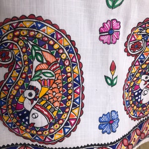 May include: White fabric with a colorful paisley design. The paisley is outlined in red and filled with a variety of colors, including blue, yellow, orange, and green. The fabric also features a border of red, yellow, and blue.