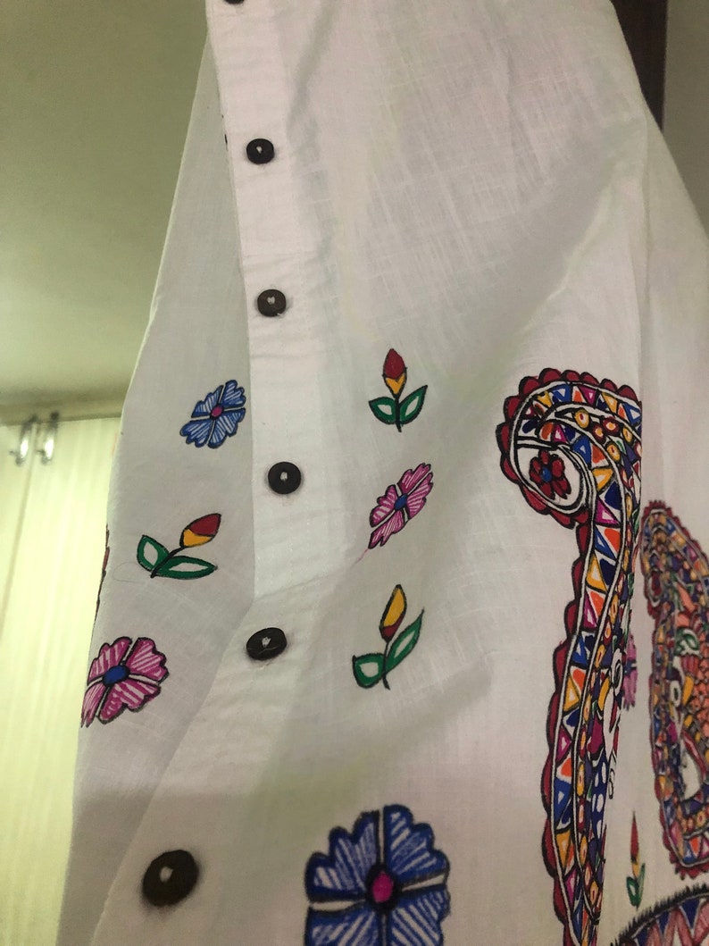 May include: White cotton shirt with a colorful paisley design and floral accents. The shirt has a button-up closure and a relaxed fit.