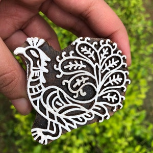 Puede incluir: Una talla de madera de un pavo real con detalles intrincados. La talla está pintada de blanco sobre un fondo marrón oscuro.