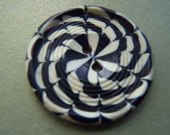 Può includere: Un bottone a due fori con un motivo a spirale bianco e nero.