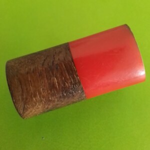 May include: A cylindrical container made of wood and red plastic with a wood grain pattern.