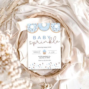 Może przedstawiać: Zaproszenie na baby shower w kolorze niebieskim i białym z motywem pączka i babeczki. Zaproszenie zawiera napis "Baby Sprinkle" oraz datę, godzinę i miejsce wydarzenia. Zawiera r&oacute;wnież informacje RSVP.