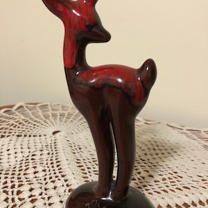 May include: A red and brown ceramic deer figurine with a gold inscription on the base that reads "Drayton".