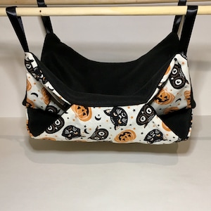 May include: A black and white fabric cat and pumpkin print hanging pet bed with black fleece lining.
