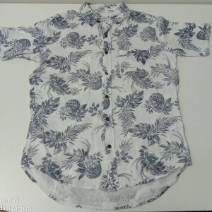 May include: A white short-sleeved button-down shirt with a blue pineapple and leaf print.