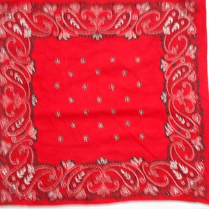 May include: Red bandana with a white paisley pattern border. The bandana is made of a soft, cotton fabric.