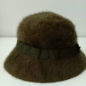 May include: A brown fuzzy bucket hat with a green ribbon around the crown.