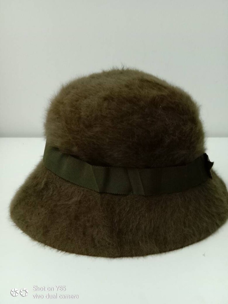 May include: A brown fuzzy bucket hat with a green ribbon around the crown.