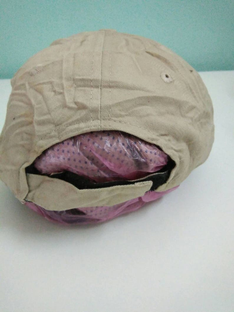 May include: A beige baseball cap with a black brim and a pink mesh lining. The cap is folded in half and the lining is visible.
