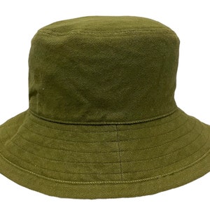 May include: A green bucket hat made of a textured fabric. The hat has a wide brim and a simple design.