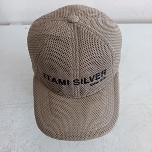 以下が含まれることがあります： 前面に黒で「ITAMI SILVER」の文字が入った、ベージュのメッシュ野球帽。 つばはカーブしており、上部に小さなボタンが付いています。 「Since 1975」の文字が下にあります。
