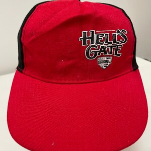 May include: Red and black baseball cap with the text "Hell's Gate" in white lettering. The cap also has a small white patch with the text "Locally Owned Original B.C. Born & Brewed".