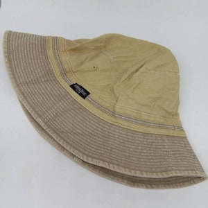 May include: A beige bucket hat with a black label that reads "Golden Bear USA".