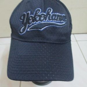 May include: A dark blue baseball cap with a white and blue embroidered logo that says "Yokohama".
