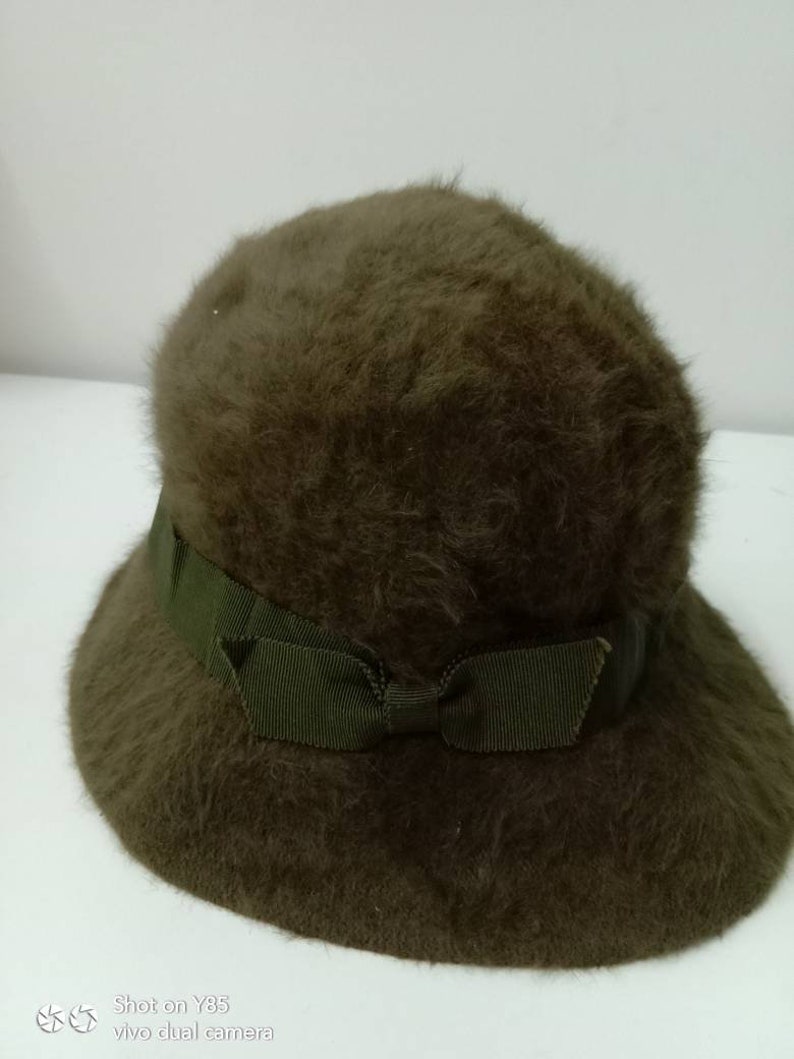 May include: A brown fuzzy hat with a green ribbon tied in a bow.