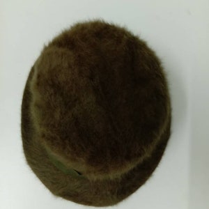 May include: A brown fuzzy bucket hat. The hat is made of a soft, plush material and has a wide brim.