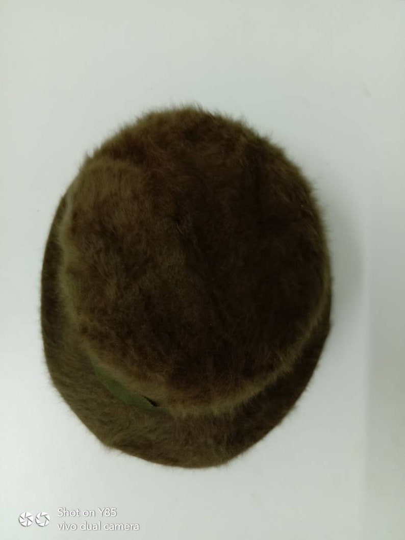 May include: A brown fuzzy bucket hat. The hat is made of a soft, plush material and has a wide brim.