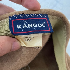 以下が含まれることがあります： Kangolのロゴと「0258BC02 LARGE」のラベルが付いた茶色の帽子。