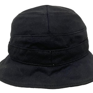 May include: A black bucket hat with a wide brim and a folded crown. The hat has a single band around the crown.