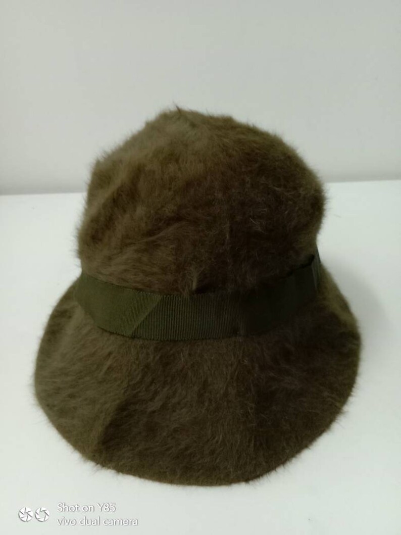 May include: A brown fuzzy bucket hat with a green ribbon around the crown.