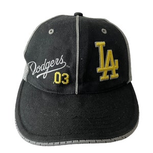 May include: Black baseball cap with a gray brim and a yellow and white embroidered "Dodgers 03" and "LA" logo.