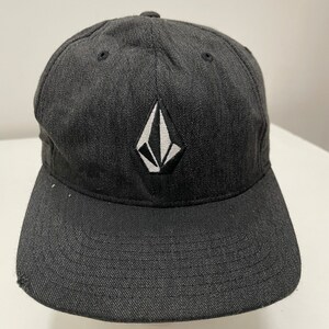 May include: A black and white embroidered logo of a diamond shape on a black baseball cap.