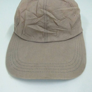 May include: A tan baseball cap with a curved brim. The cap has a six-panel design with visible stitching and a slightly wrinkled texture. The brim is also tan and has multiple rows of stitching.
