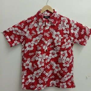 Può includere: Camicia rossa a maniche corte con bottoni e stampa floreale bianca. La camicia ha una tasca sul lato sinistro e un'etichetta che dice "altex".