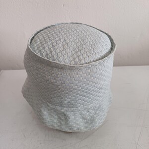 May include: A light blue and white bucket hat featuring a textured, woven checkerboard pattern throughout the crown and the brim. The hat has a rounded top and a downward-sloping brim, constructed from a soft, flexible fabric with a consistent grid design.