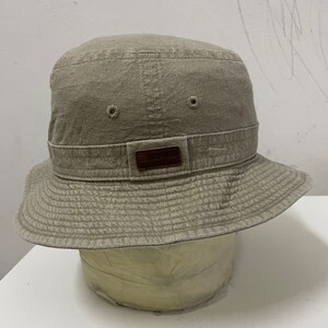 May include: A beige bucket hat with a brown leather patch that says "Burlington" on it.