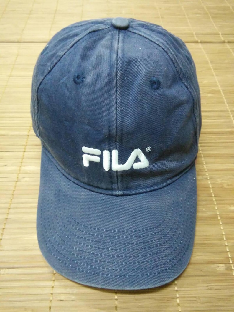 May include: A blue baseball cap with a white FILA logo embroidered on the front.