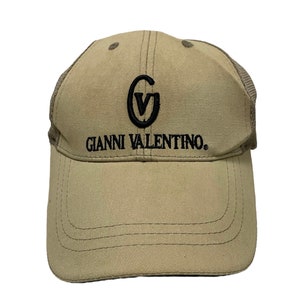 May include: A tan and black mesh baseball cap with the logo "Gianni Valentino" and a "GV" monogram.