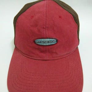 May include: Red and brown baseball cap with a black mesh back. The cap has a white oval logo with the text "Since 1921 McGregor" in black.