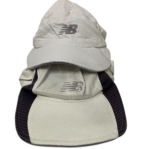 May include: Two white running hats with black accents and a grey New Balance logo. The top hat is a solid white with a grey logo. The bottom hat has a black mesh panel on the side and a grey logo.