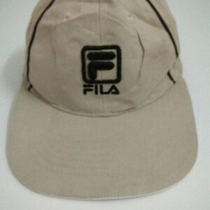 May include: A beige baseball cap with a black Fila logo on the front.