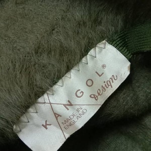 May include: A green Kangol hat with a white label that reads "Kangol Made in England Design".