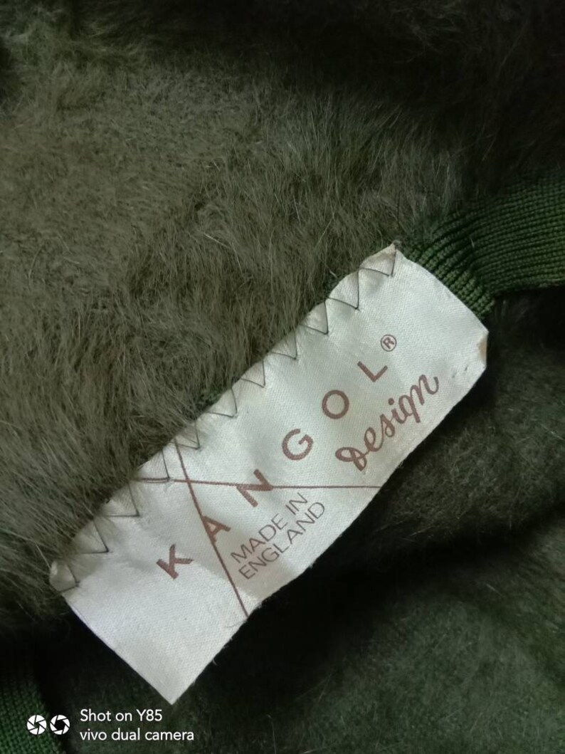 May include: A green Kangol hat with a white label that reads "Kangol Made in England Design".