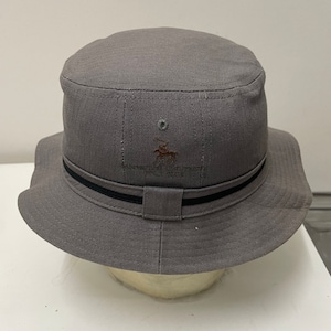 May include: A gray bucket hat with a black band and a brown embroidered logo of a horse rider. The logo says "Cavaliers Country Club".