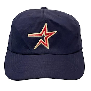 May include: A navy blue baseball cap with a red and white star embroidered on the front.